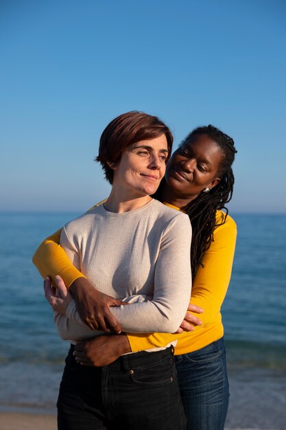 Pareja de lesbianas de tiro medio en la playa