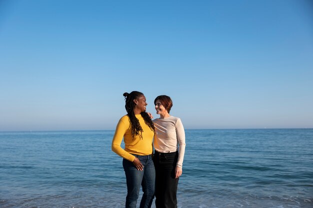 Pareja de lesbianas de tiro medio en la playa