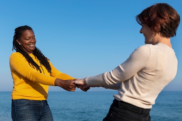 Pareja de lesbianas de tiro medio en la playa