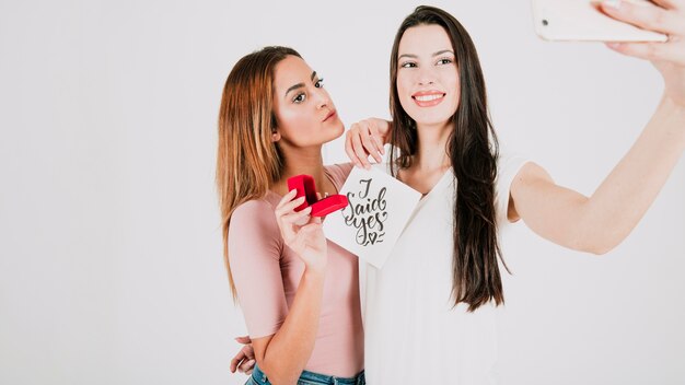 Pareja de lesbianas tomando selfie con anillo de propuesta