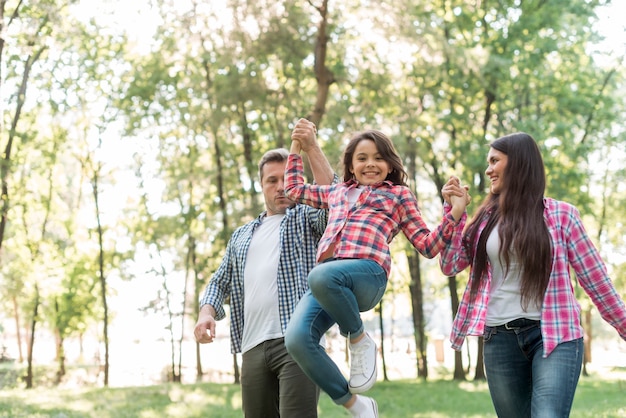 Pareja levantando a su hija mientras caminaba en el parque