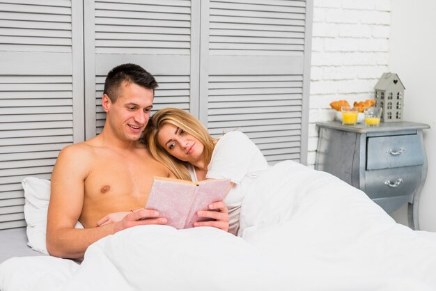 Pareja leyendo libro en la cama