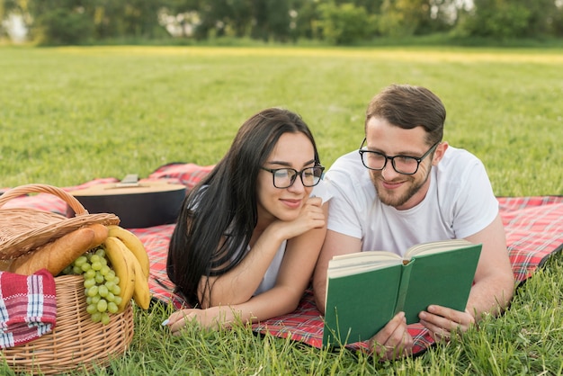 Pareja leyendo sobre manta de picnic