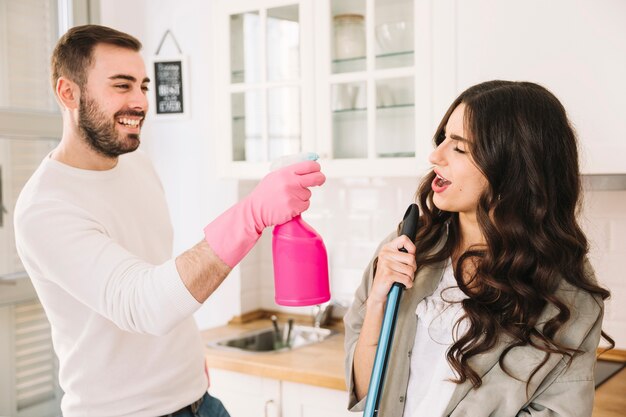 Pareja limpiando cocina y jugando juntos