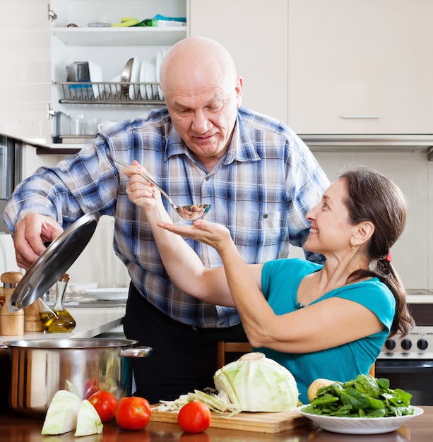 pareja madura cocinando comida con verduras