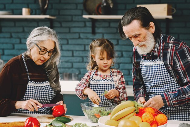 Pareja madura y su nieta preparando la comida