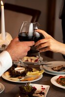 Foto gratis pareja manos animando copas de vino tinto en la cena
