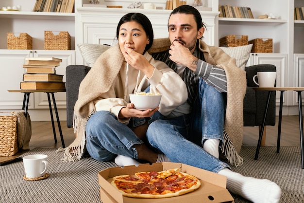 Pareja en manta comiendo pizza y palomitas de maíz