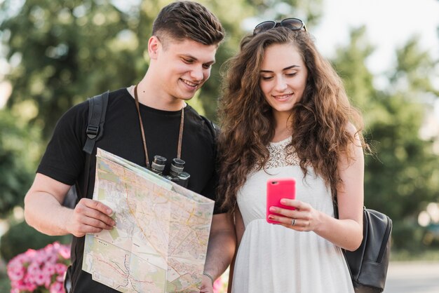 Pareja con mapa usando teléfono inteligente