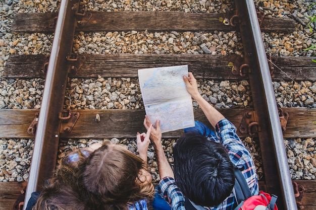 Foto gratuita pareja con mapa en vías de tren vista superior