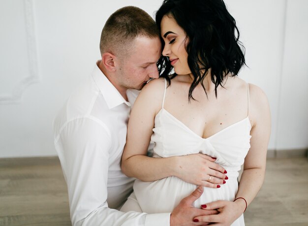 Pareja de marido guapo y mujer bonita pragnant posando en estudio