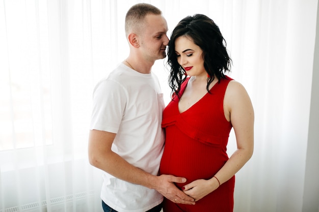 Pareja de marido guapo y mujer bonita pragnant posando en estudio