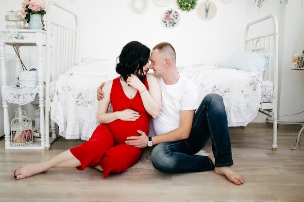 Pareja de marido guapo y mujer bonita pragnant posando en estudio