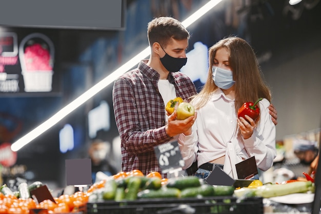 Pareja en máscara protectora médica en un supermercado.