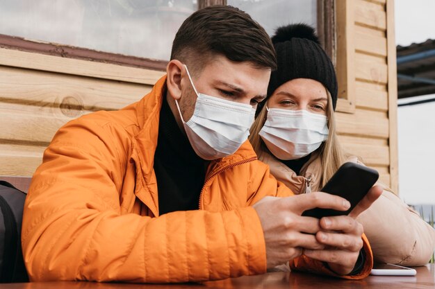 Pareja con máscaras y smartphone