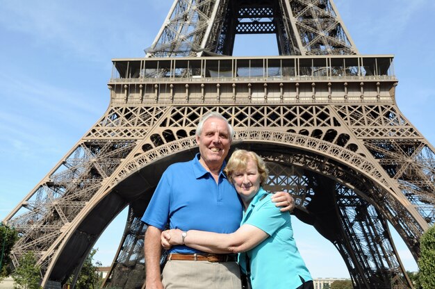 Pareja mayor abrazandose en frente de la torre eiffel en parís