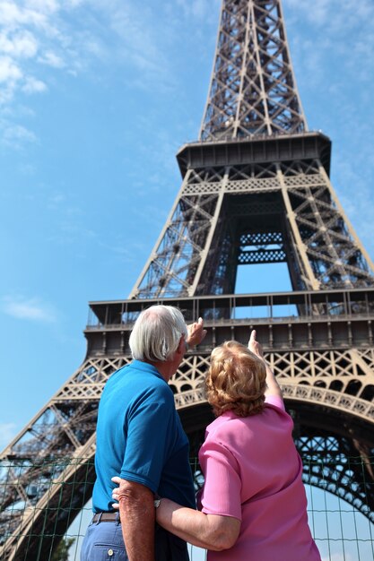 Pareja mayor apuntando a la torre eiffel en parís