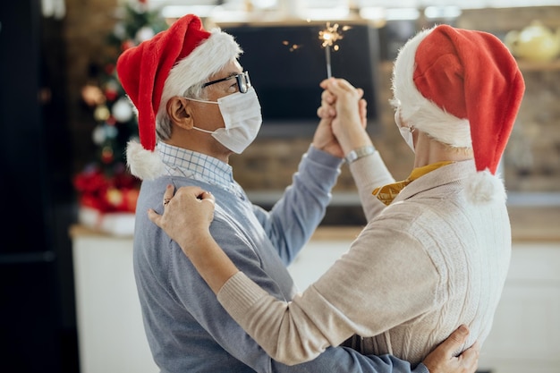 Pareja mayor bailando mientras celebra Navidad en casa durante la pandemia de COVID19