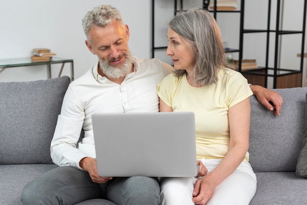 Pareja mayor, en casa, en el sofá, usar la computadora portátil