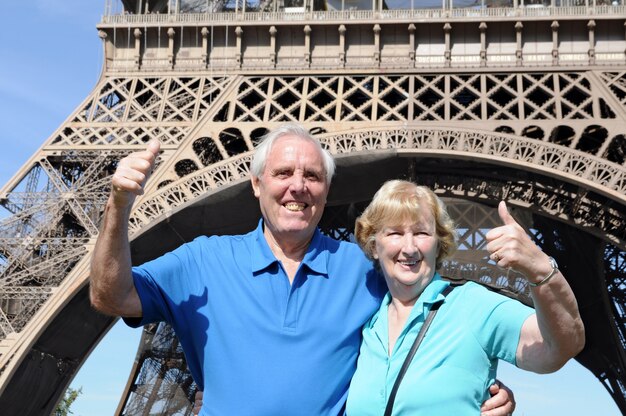 Pareja mayor delante de la torre eiffel en parís