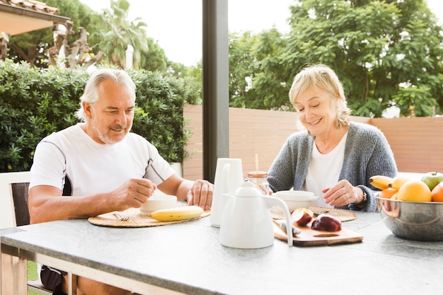 Pareja mayor desayunando en jardín