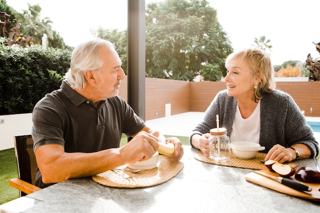 Pareja mayor desayunando en jardín