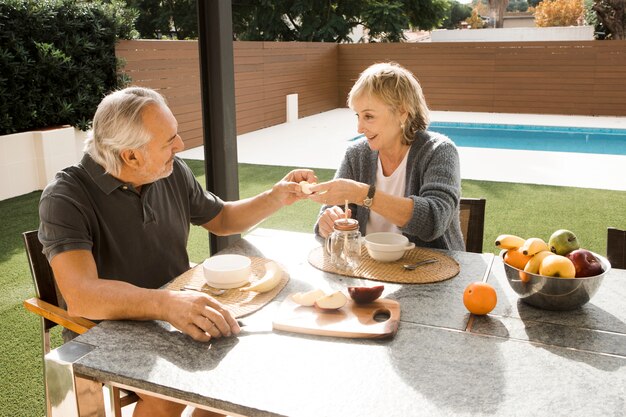 Pareja mayor desayunando en jardín