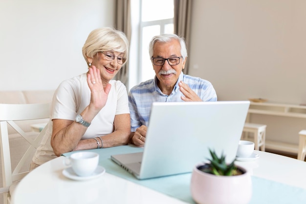 Una pareja mayor está hablando en línea a través de una conexión de video en la computadora portátil Pasando un buen rato con amigos y familiares a través de una videollamada