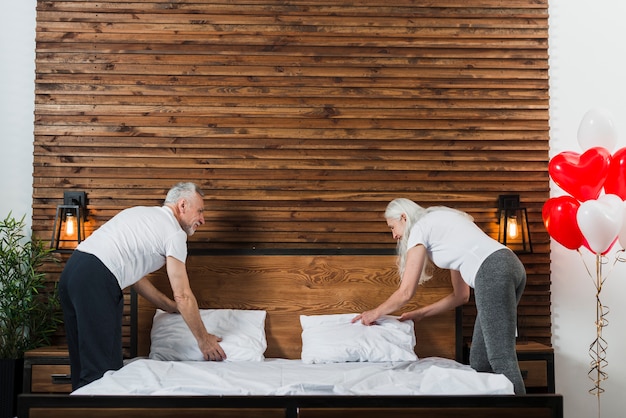 Foto gratuita pareja mayor, hacer cama, juntos