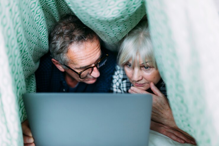 Foto gratuito pareja mayor juntos en cama con portátil