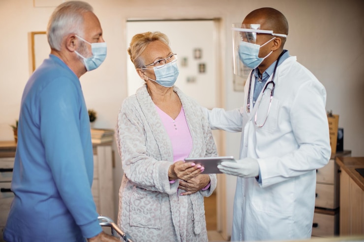 Foto gratuito pareja mayor y médico negro con máscaras faciales mientras usa el panel táctil en el hogar de ancianos