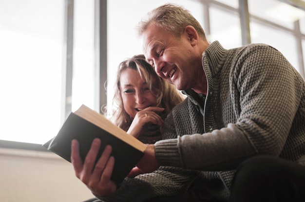 Foto gratuita pareja mayor, reír, de, libro