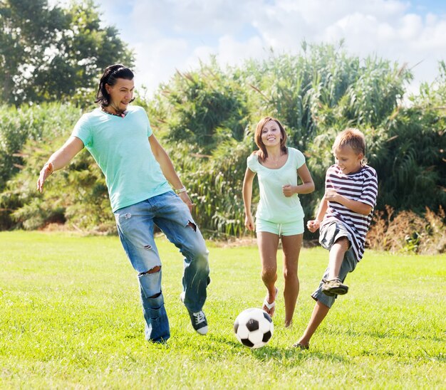 Pareja de mediana edad y adolescente jugando con balón de fútbol