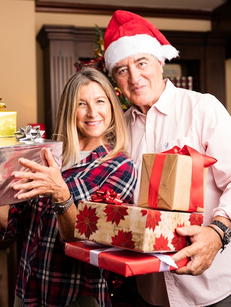 Pareja de mediana edad posando con muchos regalos