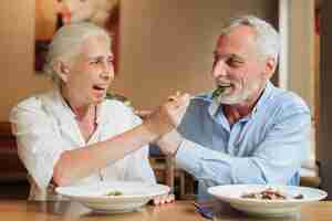 Foto gratuita pareja mediana de tiro viejo alimentándose unos a otros