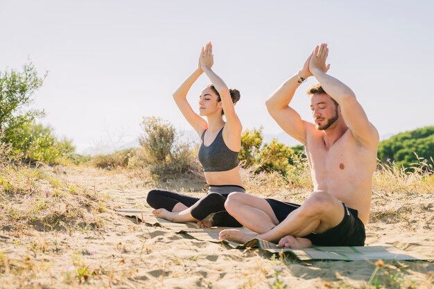 Pareja meditando juntos por la playa