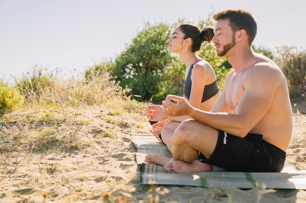 Pareja meditando por la playa