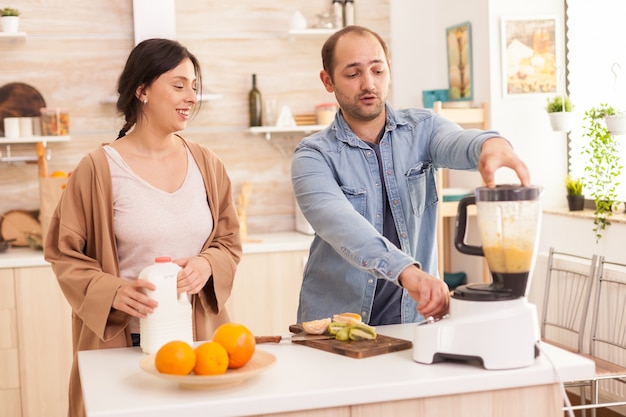 Pareja mezclando varias frutas para batidos nutritivos y saludables. Estilo de vida saludable, despreocupado y alegre, comiendo dieta y preparando el desayuno en una acogedora mañana soleada