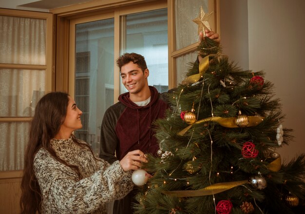 Pareja mirando el uno al otro mientras decorando el árbol