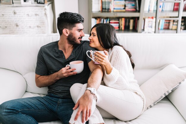 Pareja mirando el uno al otro sosteniendo la taza de café en las manos