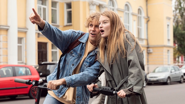 Pareja mirando algo mientras en scooters eléctricos en la ciudad