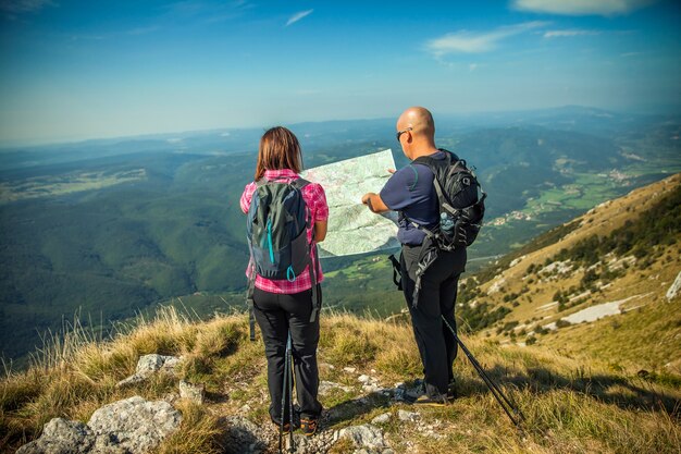 Pareja mirando un mapa en Nanos Plateau en Eslovenia con vistas al valle de Vipava