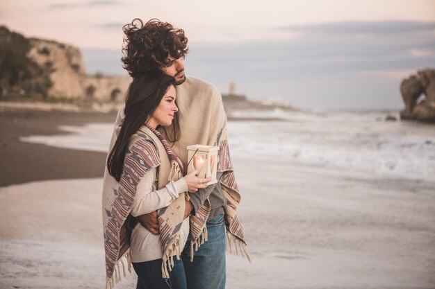 Pareja mirando el mar mientras sujetan una vela