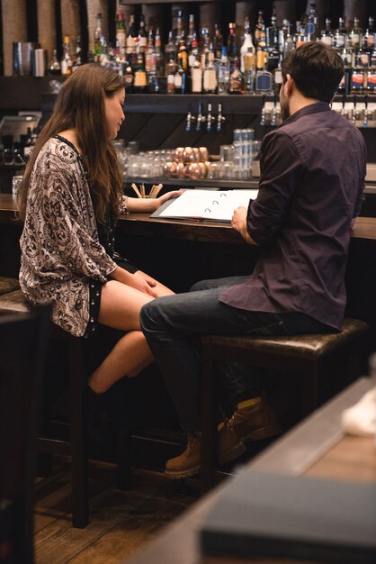 Pareja mirando el menú en la barra de bar