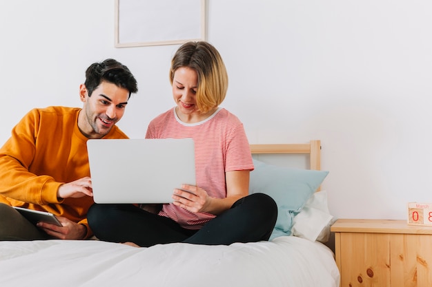 Pareja mirando portátil en la cama