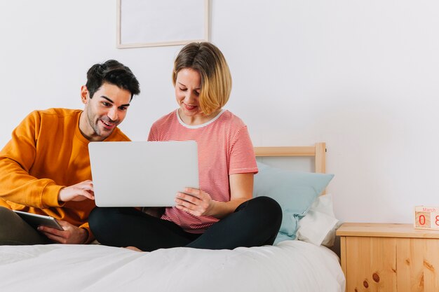 Pareja mirando portátil en la cama