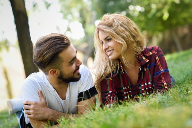 Pareja mirándose a los ojos tumbada en el césped