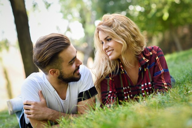 Pareja mirándose a los ojos tumbada en el césped