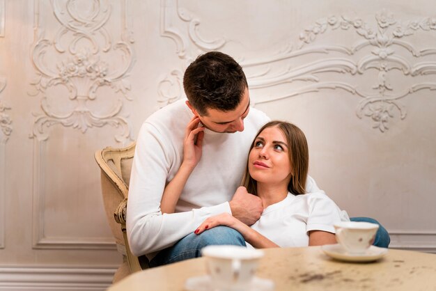 Pareja mirándose con tazas de té desenfocadas