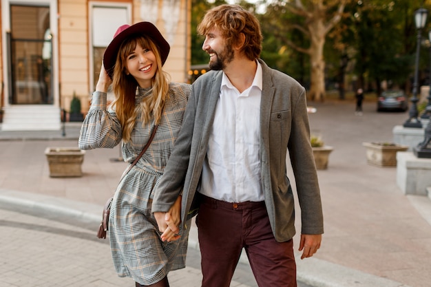 Pareja de moda atractiva posando en la calle vieja en primavera soleada. Mujer muy hermosa y su novio elegante guapo abrazos al aire libre.